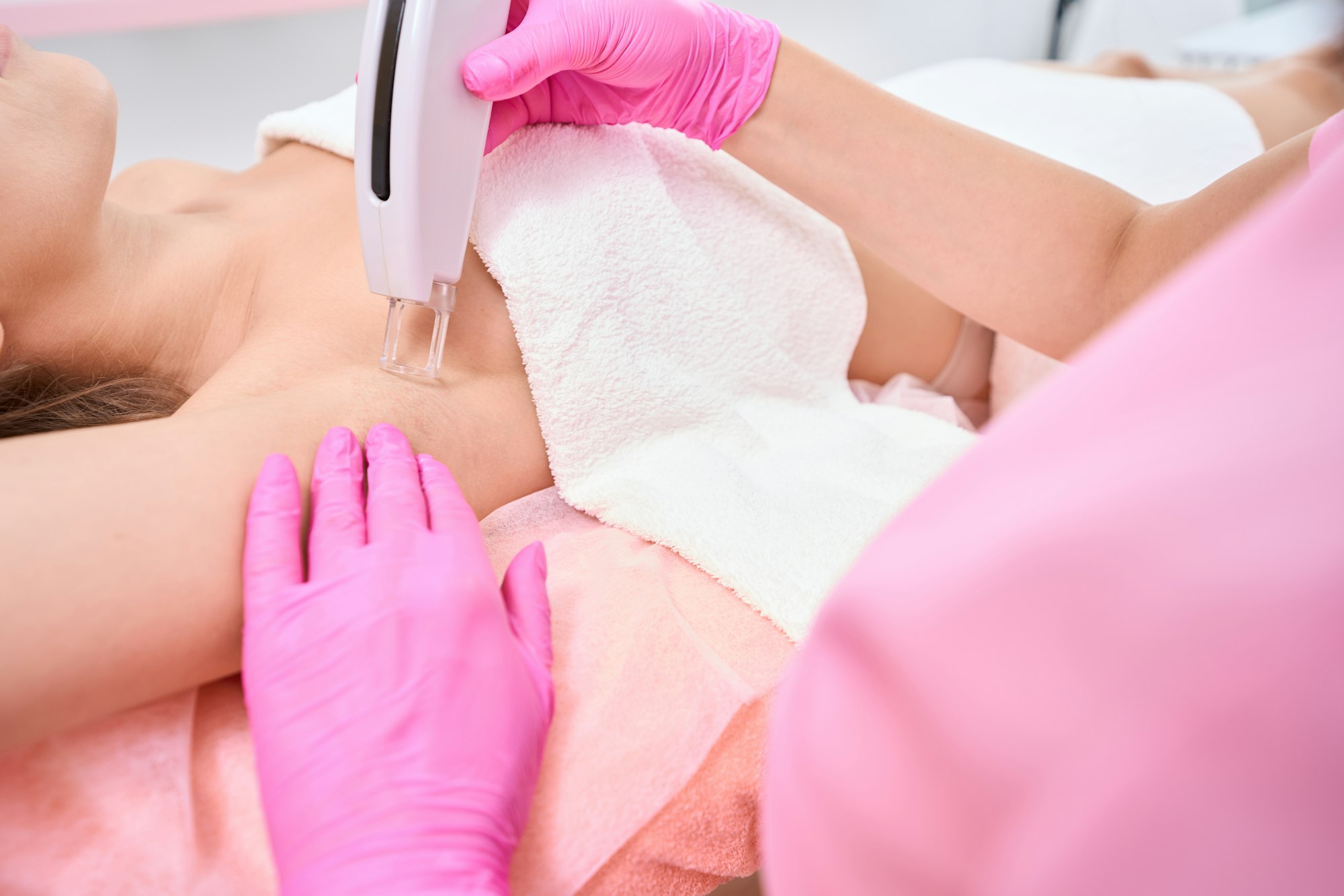 Beautician performs laser hair removal procedure in armpits of lady